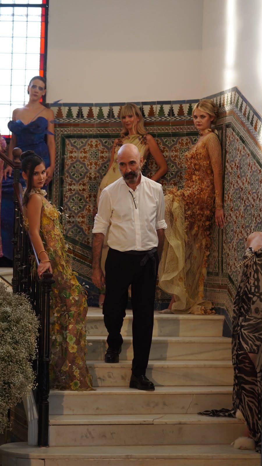 Julio Diaz en la escalera del palacete durante el desfile, entre modelos