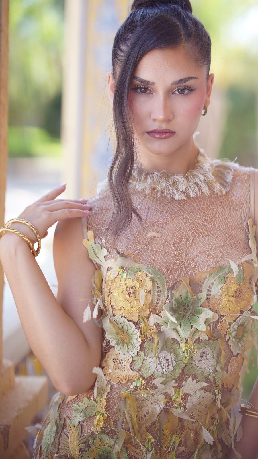 Modelo con el vestido Azahar de pétalos dorados, mano en alto